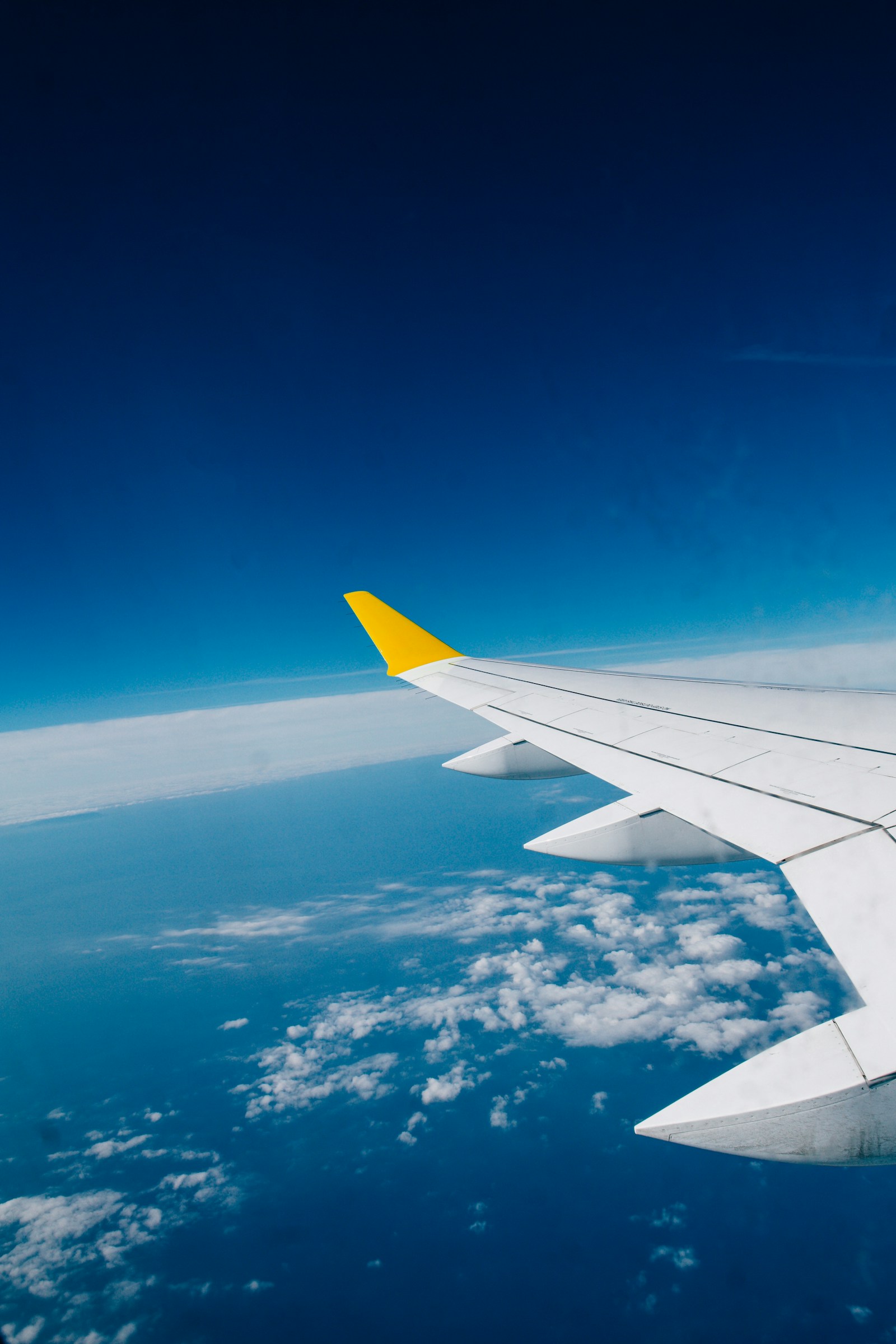 An aircraft wing above a layer of clouds — photograph by Christian Lue on Unsplash