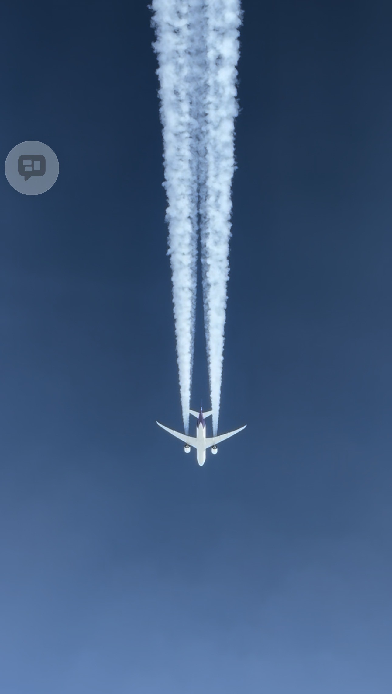 An airliner overhead leaving twin white contrails across the sky