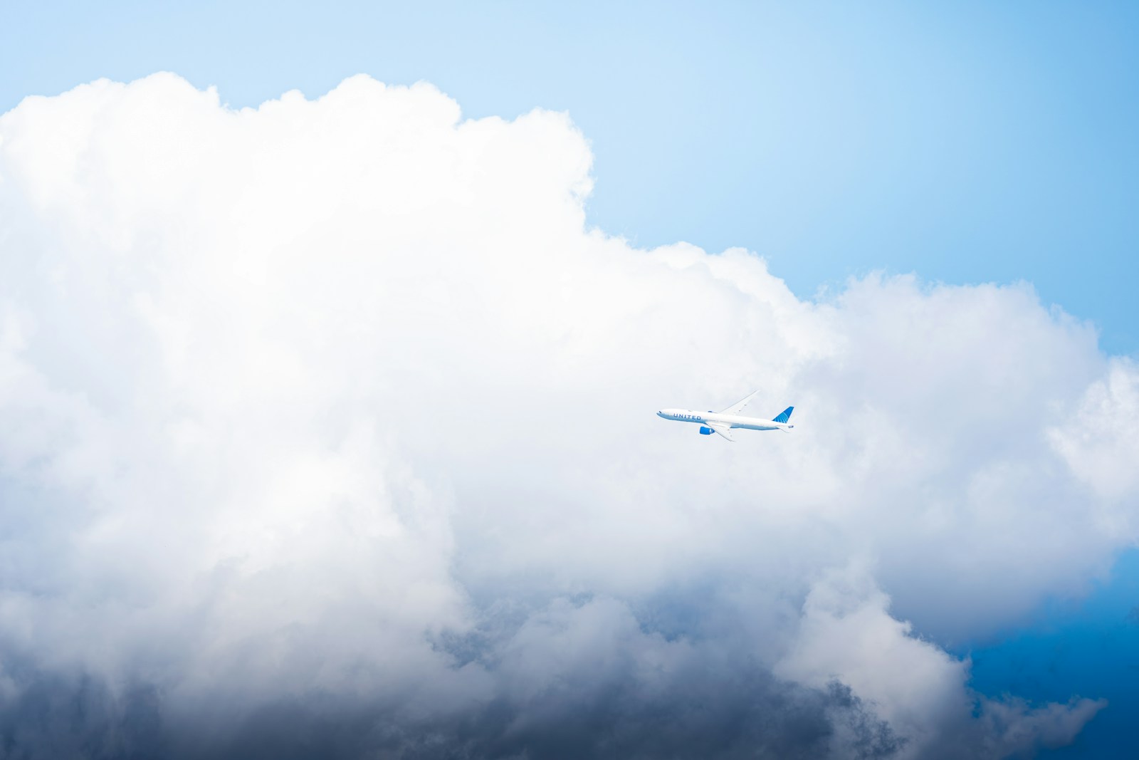 An airliner flying beside towering clouds — photograph by Hieu on Unsplash