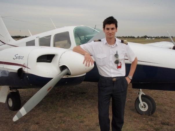 A younger Alessio in pilot uniform beside a twin-engine aircraft
