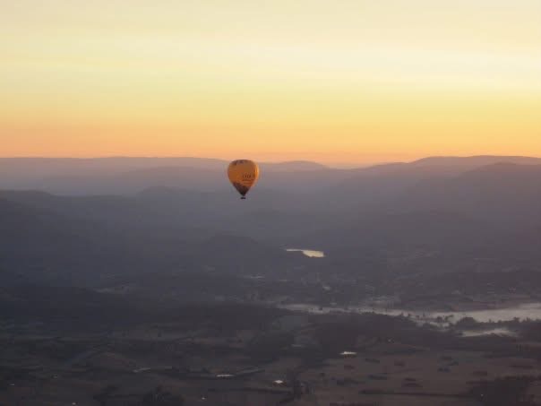 A hot-air balloon floating over a misty valley at sunrise
