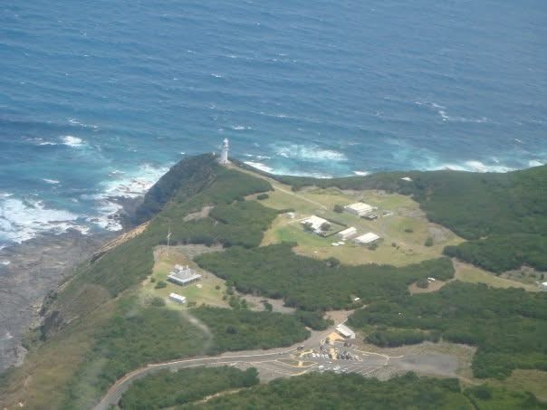 A coastal headland and lighthouse seen from an aircraft
