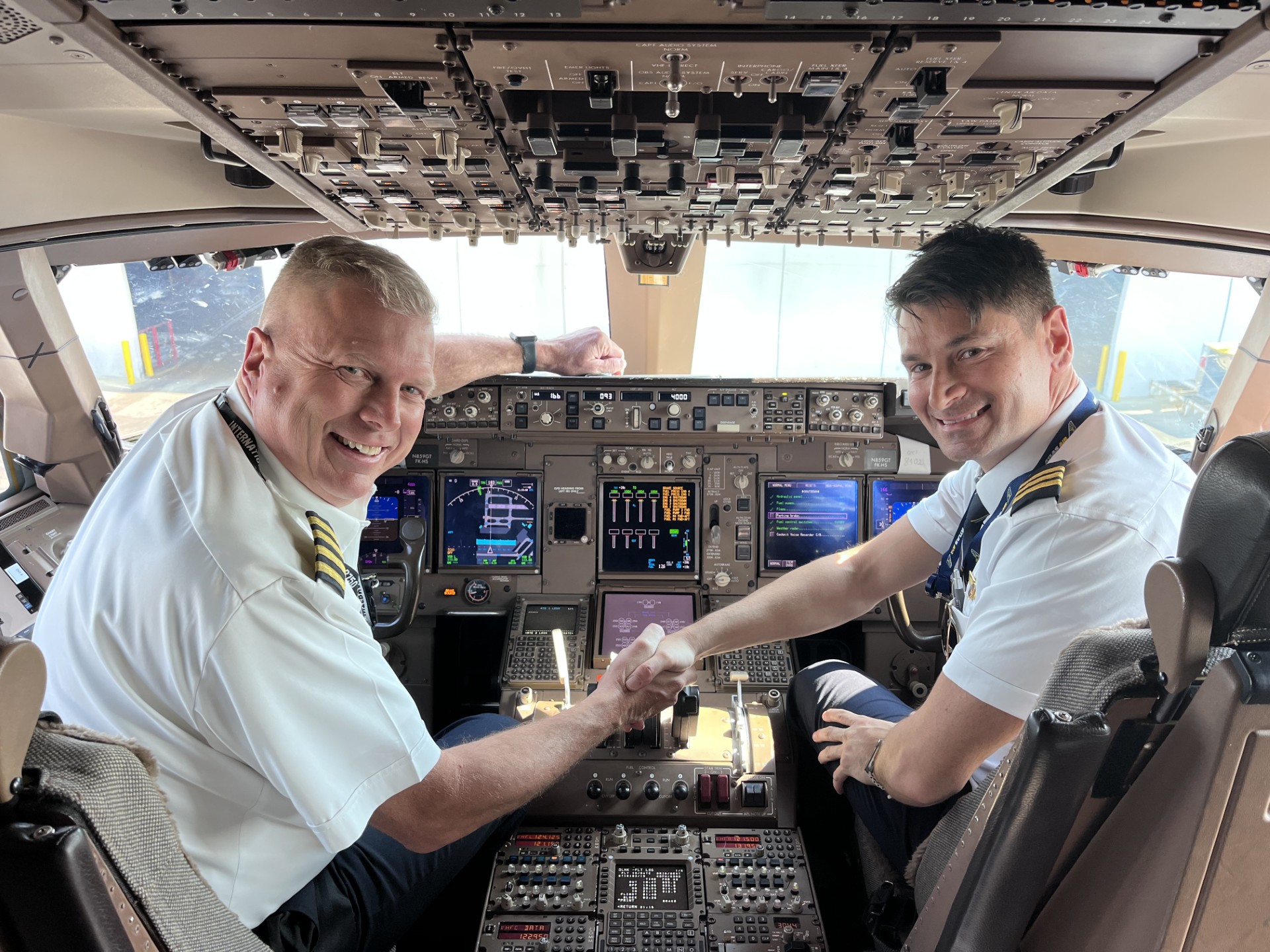 Alessio and a fellow pilot shaking hands in an airliner cockpit