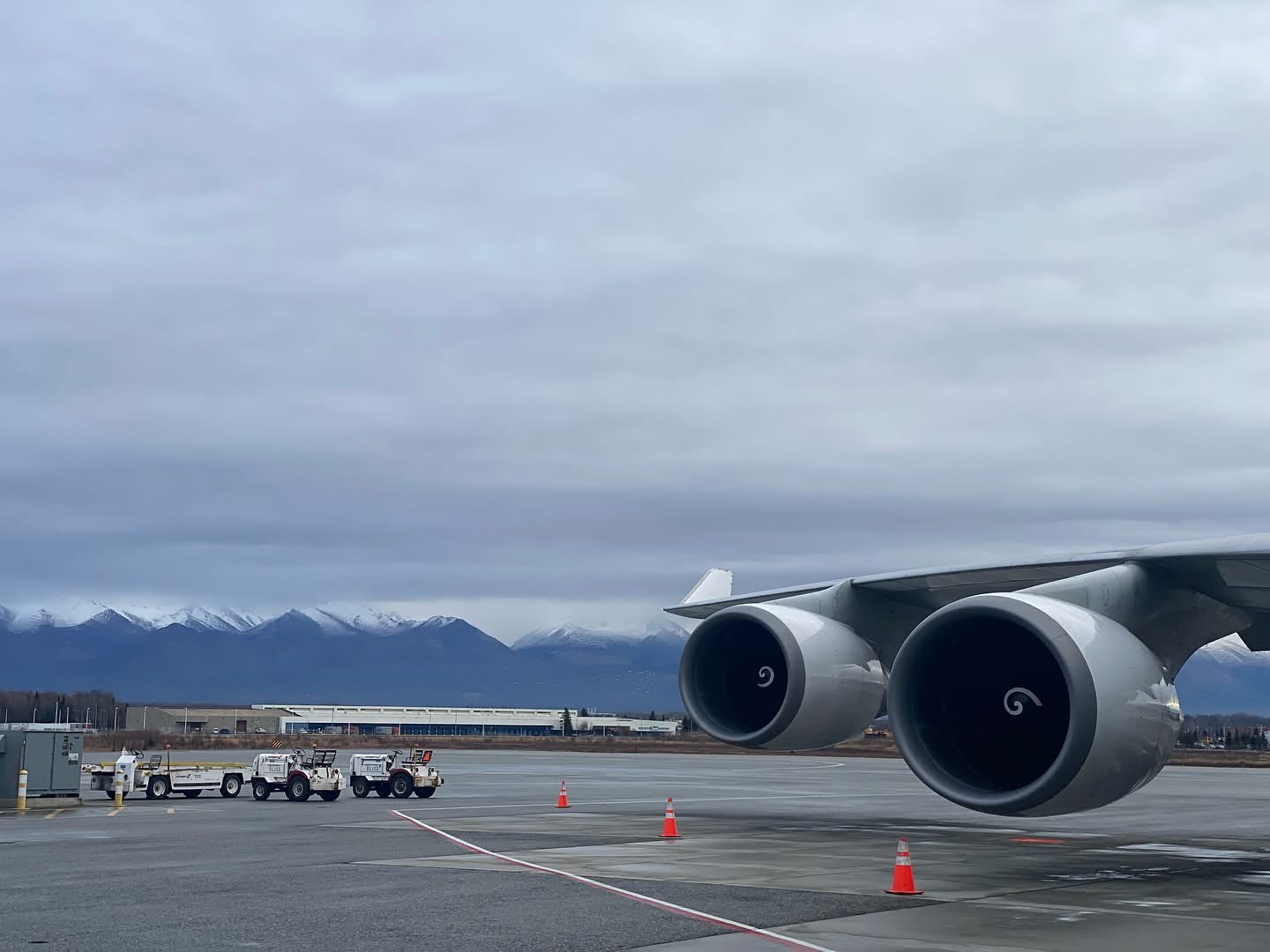 Two jet engines above an apron with mountains beyond