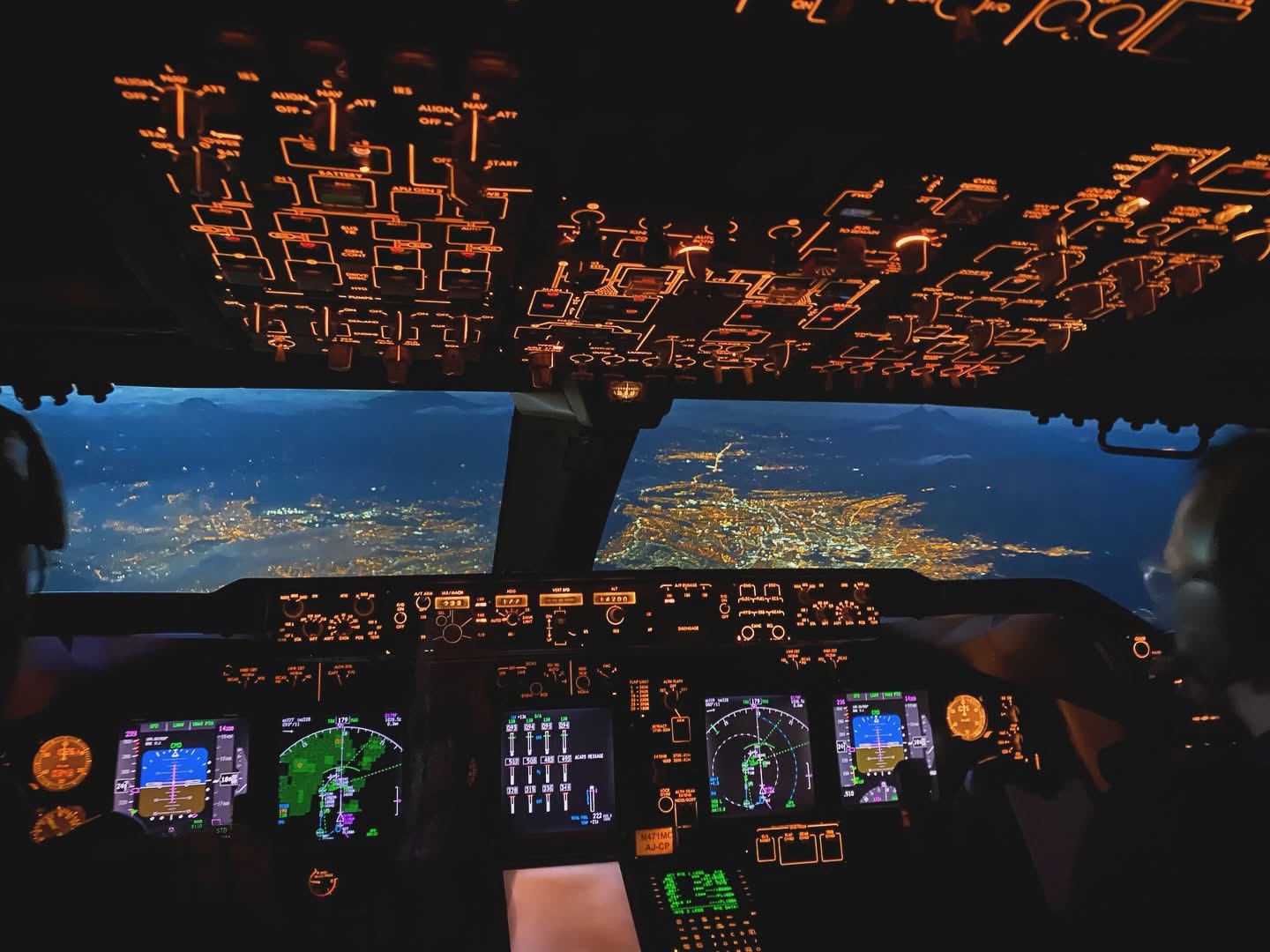 Illuminated flight-deck instruments with city lights beyond the windscreen