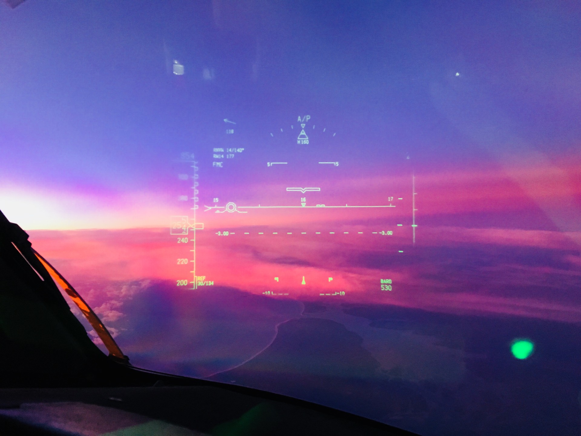 A cockpit heads-up display against clouds and the sunset horizon