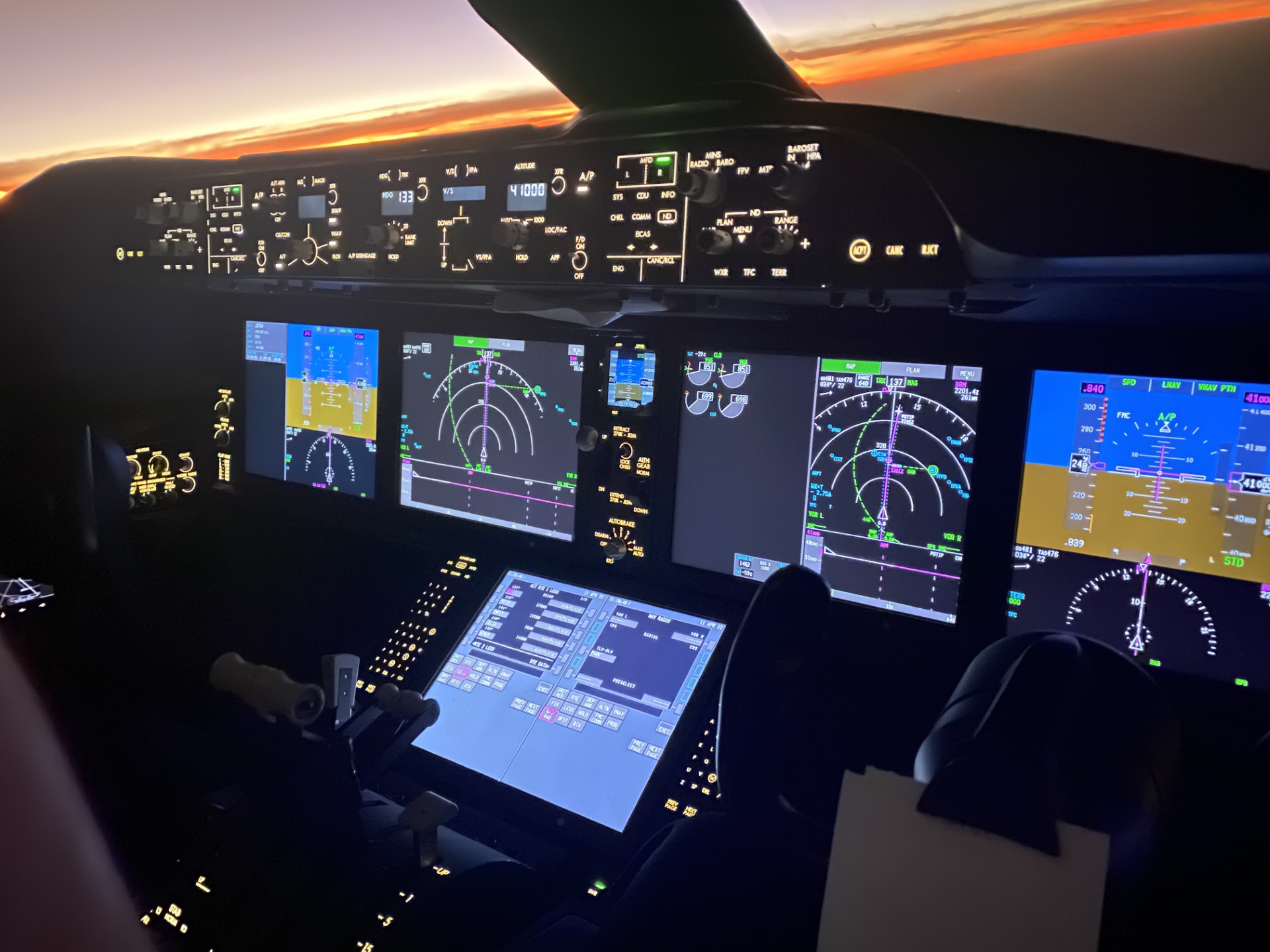 Illuminated airliner instruments beneath a sunset horizon