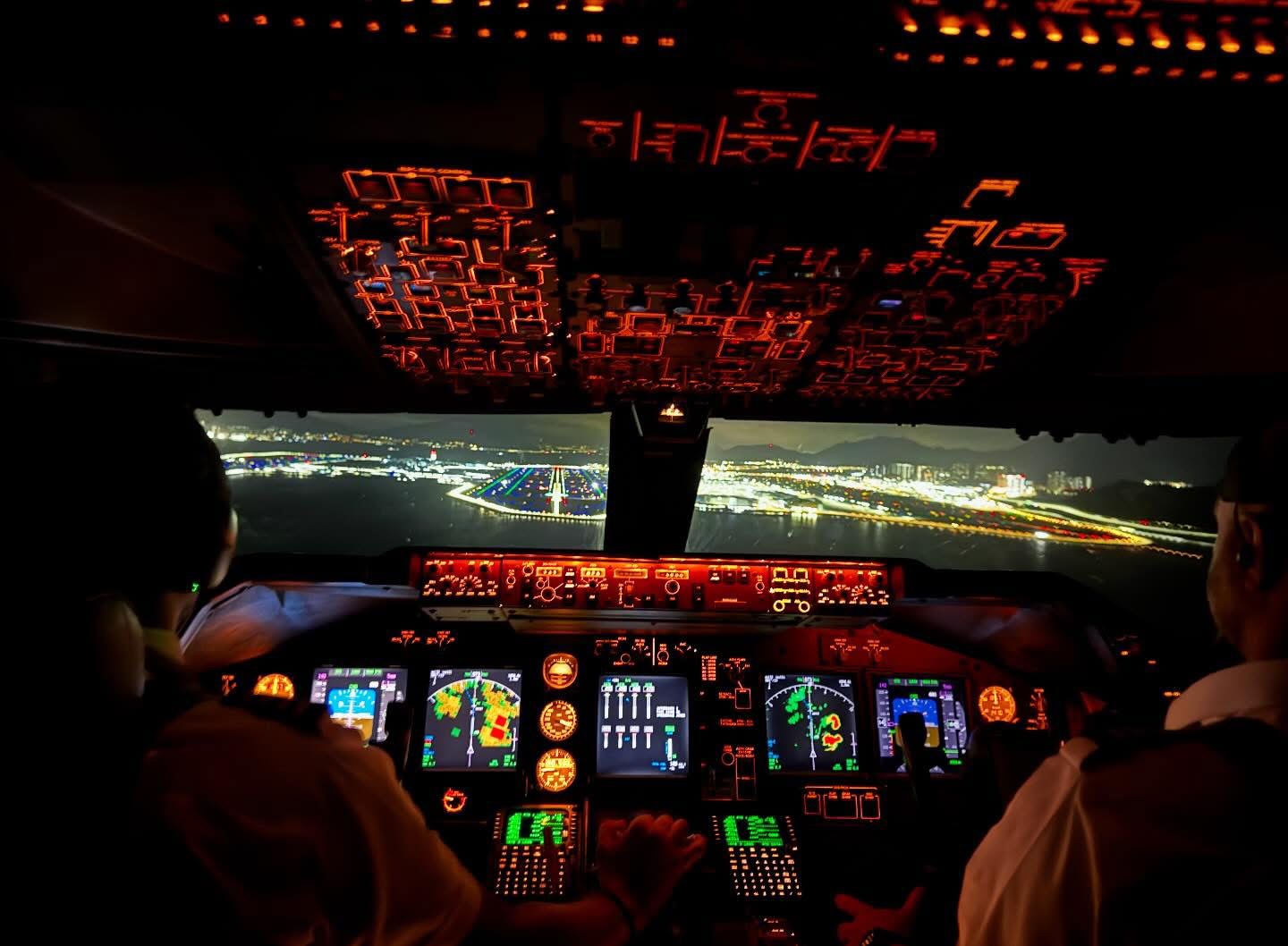 Airliner crew and illuminated cockpit instruments during a night approach