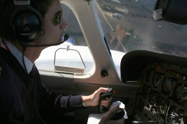 A headset-wearing pilot at the controls of a light aircraft