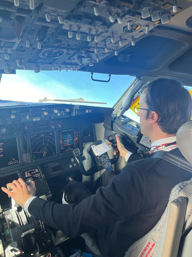 A pilot in a headset at the controls of an airliner
