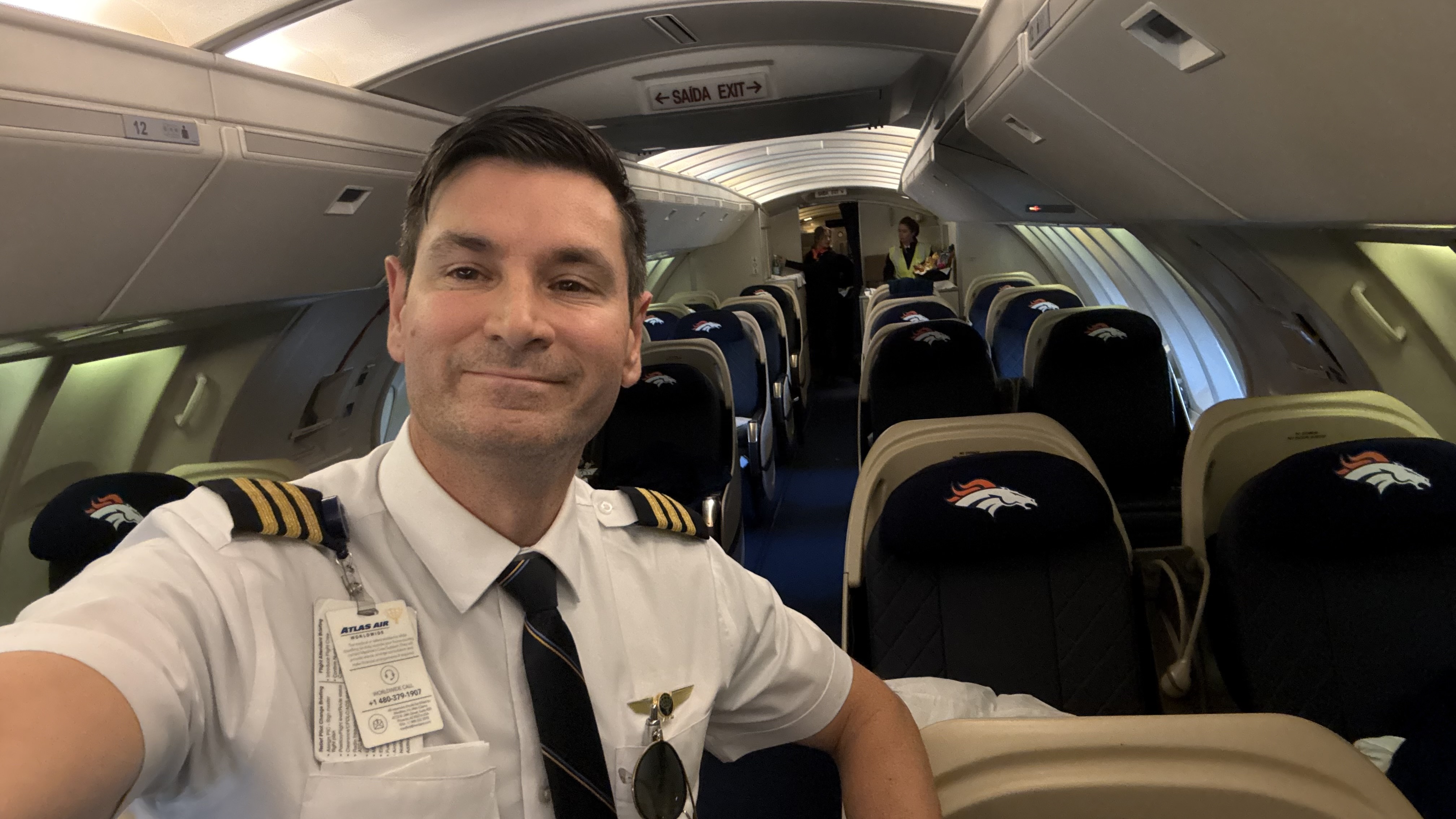 A pilot in uniform inside an aircraft passenger cabin