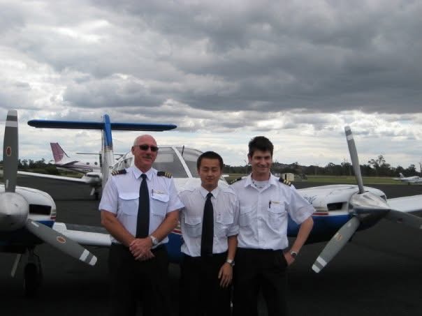 Three pilots in uniform standing together beside a light aircraft