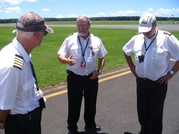 Three pilots talking together on an airfield apron