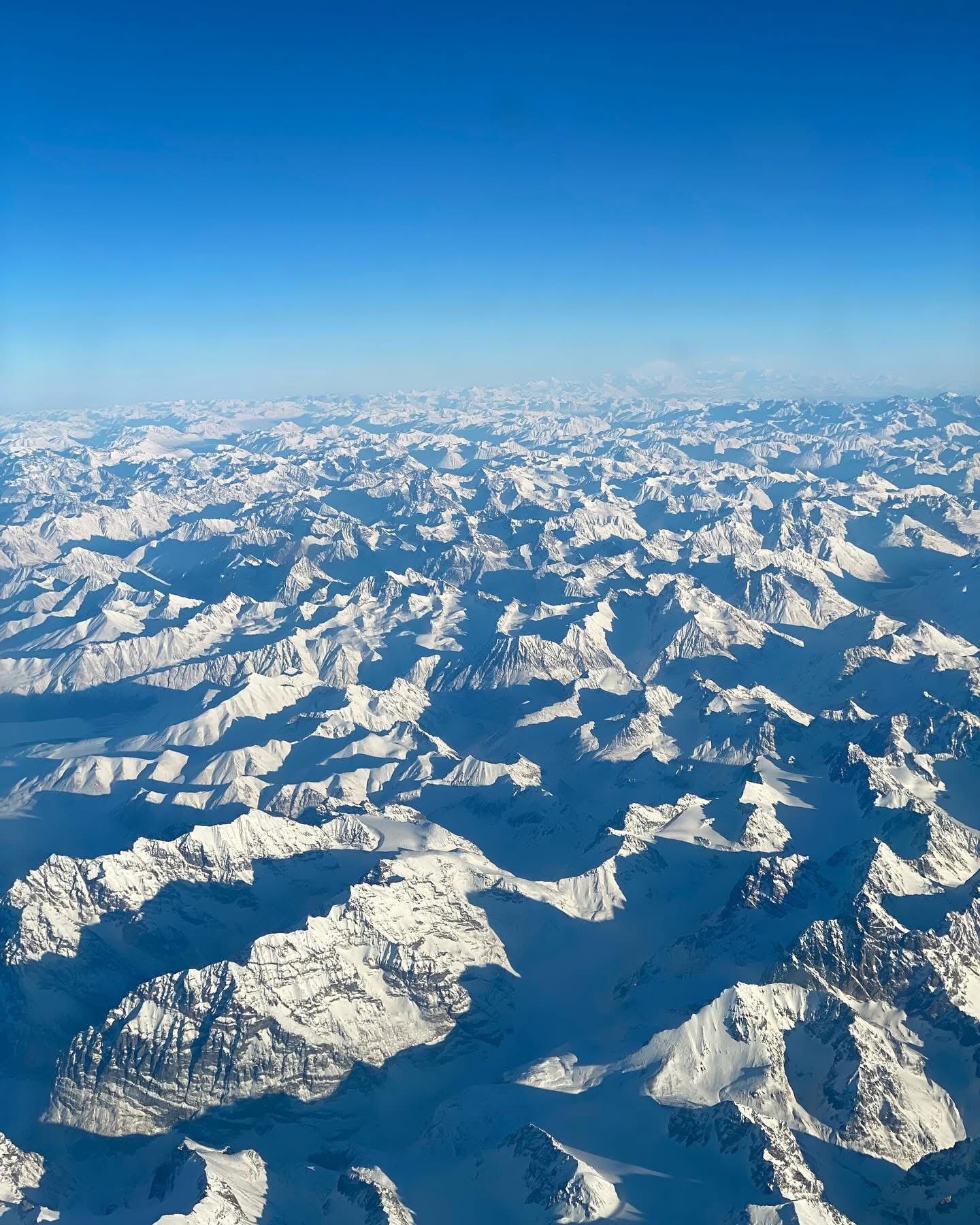 A sweeping view of snow-covered mountain peaks from the sky