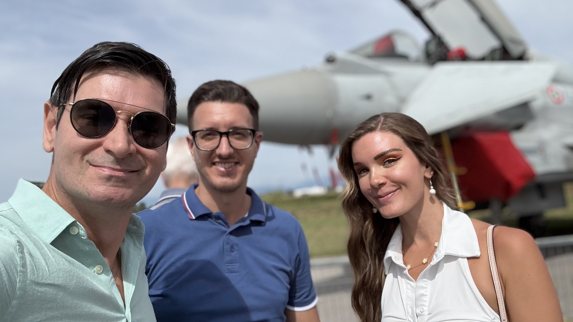 Three visitors sharing a moment beside a fighter aircraft on display